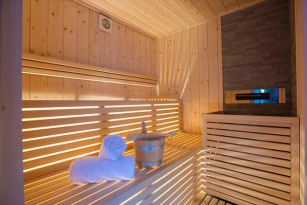 Drevená sauna s lavicami, uterákom a vedrom s naberačkou.