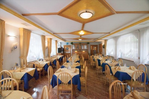 Elegantný interiér reštaurácie s dreveným nábytkom a modro-béžovými obrusmi.
