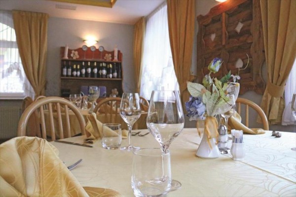 Reštaurácia s elegantne prestretým stolom, pohármi a kvetinovou ozdobou.