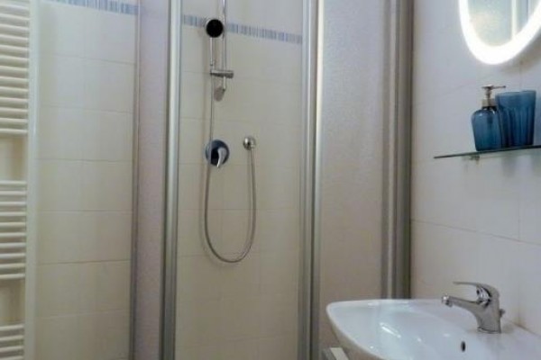 Moderná kúpeľňa so sprchovým kútom, umývadlom a zrkadlom.