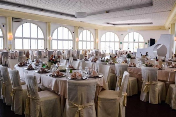 Elegantne prestretá jedáleň s okrúhlymi stolmi a bielymi poťahmi na stoličkách.