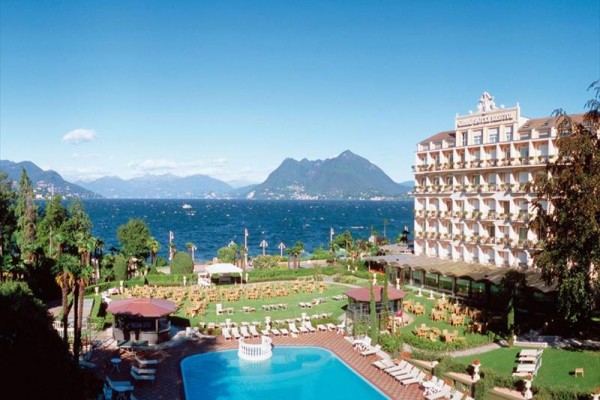 Hotel pri jazere s bazénom a horami v pozadí.