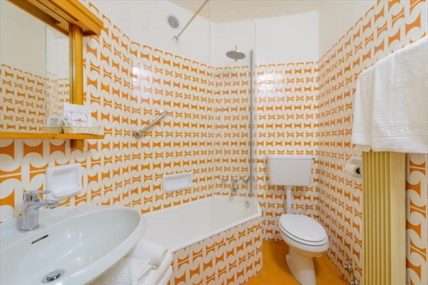 Retro kúpeľňa s oranžovými obkladmi a vaňou.