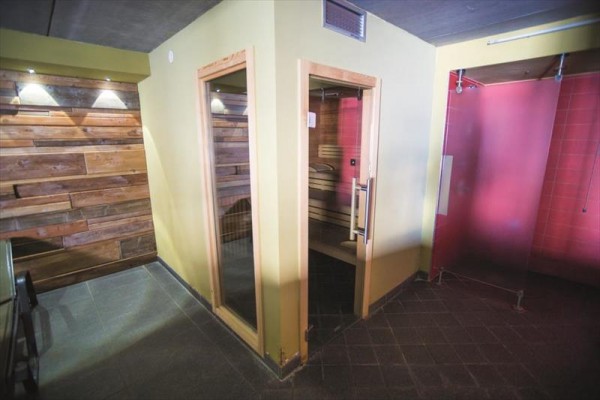 Sauna s dreveným obložením a sklenenými dverami vedľa sprchy.