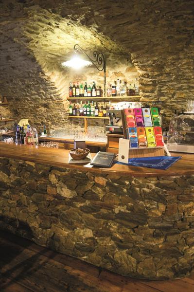 Bar s kamenným pultom a výberom nápojov v útulnej miestnosti.