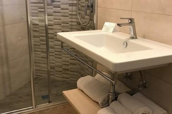 Moderná kúpeľňa s umývadlom, sprchovacím kútom a uterákmi.