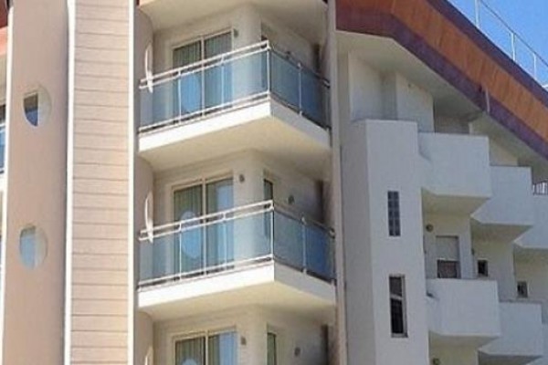 Moderná budova s balkónmi a modrými sklenenými zábradliami.