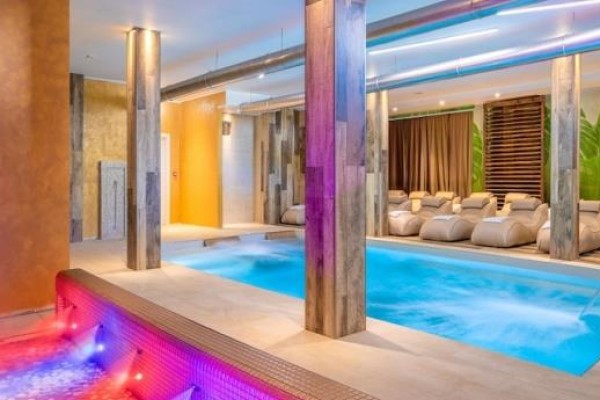 Moderné wellness centrum s bazénom a vírivkou obklopenou ležadlami.