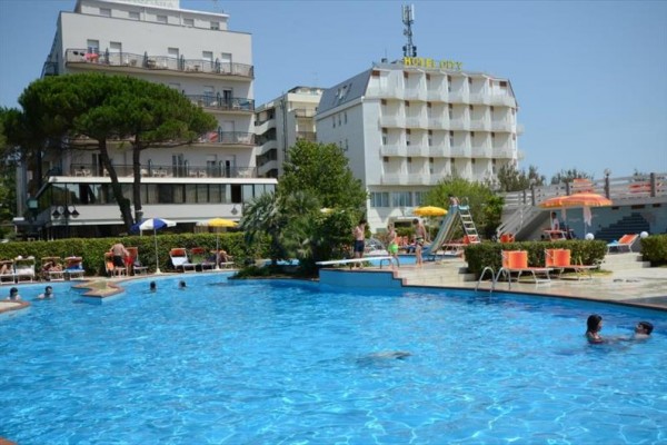 Vonkajší bazén s ľuďmi a v pozadí niekoľkoposchodový hotel.