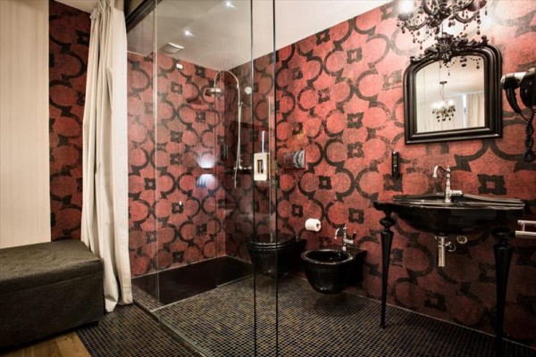 Elegantná kúpeľňa s výraznými červenými vzormi na stenách a čiernym sanitárnym vybavením.