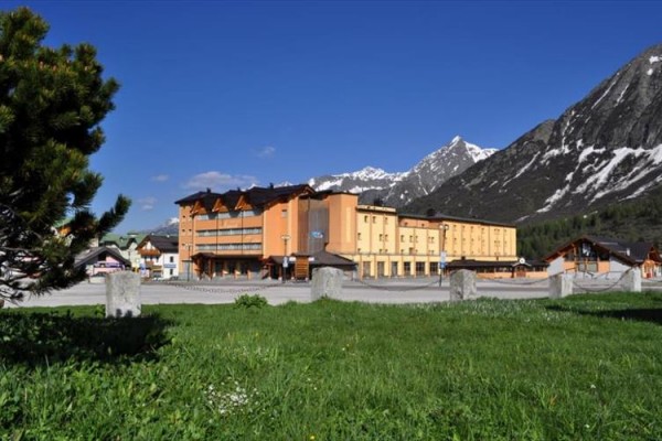 Hotel na lúke s horskou krajinou v pozadí.