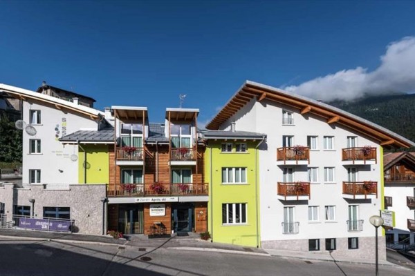 Moderná budova s drevenými balkónmi na horskej ulici.