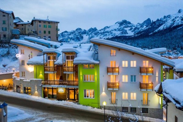 Snehom pokrytý horský hotel s drevenými balkónmi v zimnej krajine.  