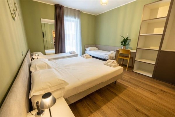 Izba s manželskou posteľou, samostatným lôžkom, písacím stolom a otvorenou policou.