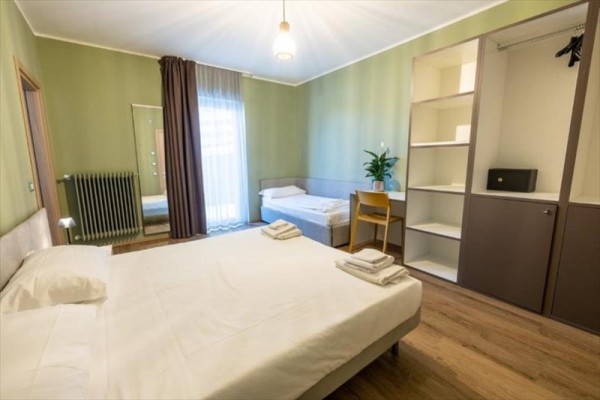 Moderne zariadená spálňa s manželskou posteľou, jednolôžkom, skriňou a zrkadlom.