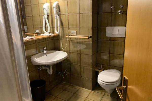 Kúpeľňa s umývadlom, toaletou a dvoma sušičmi na stene.