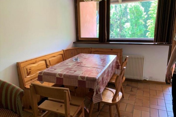 Jedálenský kút s dreveným stolom a stoličkami pri okne s výhľadom na stromy.