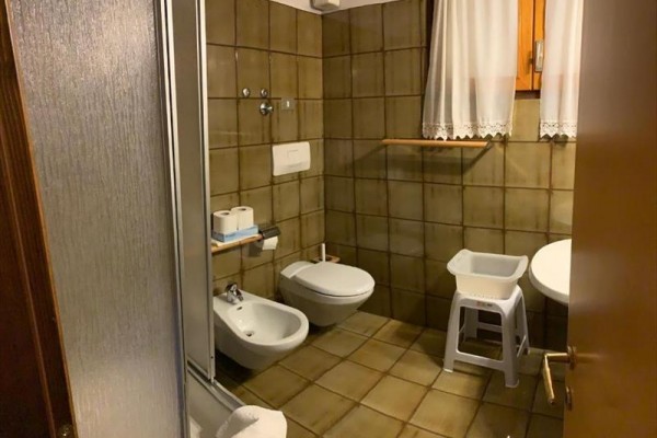 Kúpeľňa s bidetom a toaletou, obložená hnedými kachličkami.