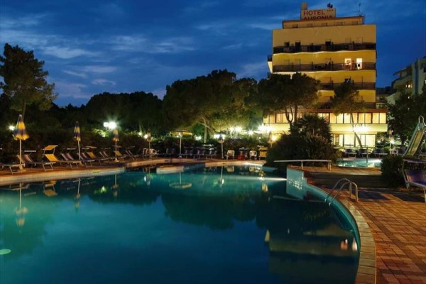 Osvetlený hotel a bazén v noci.