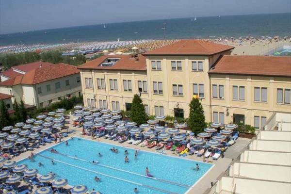 Hotel s bazénom a plážou v pozadí.