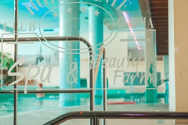 Sklenené dvere vedúce k bazénu s nápisom Hotel Dante Spa & Beauty Farm.