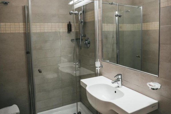 Moderná kúpeľňa so sprchovacím kútom a umývadlom s veľkým zrkadlom.