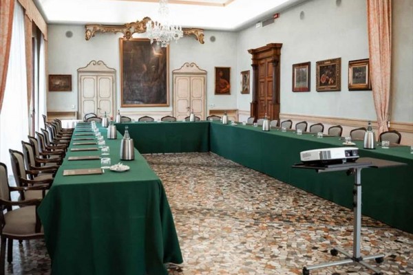 Konferenčná miestnosť s usporiadaním v tvare U, zelenými obrusmi a projektorom.
