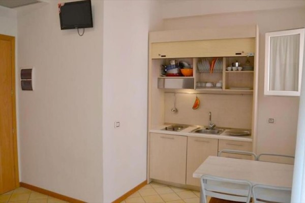 Malá kuchynská linka s drezom, stolom a stoličkami v rohu miestnosti.