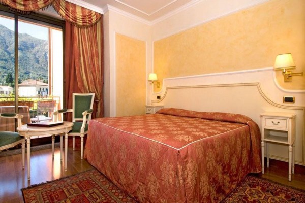 Elegantná hotelová izba s manželskou posteľou a výhľadom na hory.
