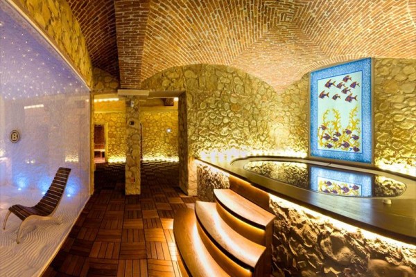 Luxusný interiér wellness centra s vírivkou a dekoráciou na kamennej stene.