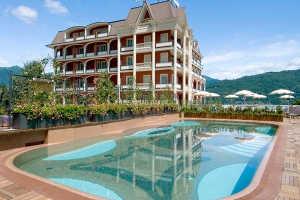 Hotel s vonkajším bazénom a horami v pozadí.  