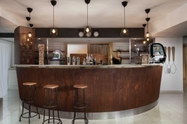 Moderný bar s dreveným pultom, stoličkami a závesnými svietidlami.