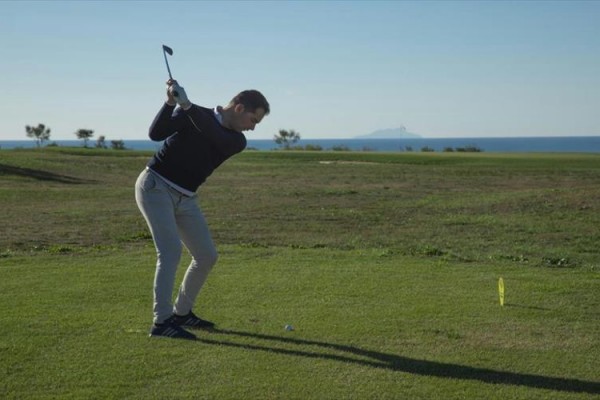 Muž na golfovom ihrisku sa chystá odpáliť loptičku.