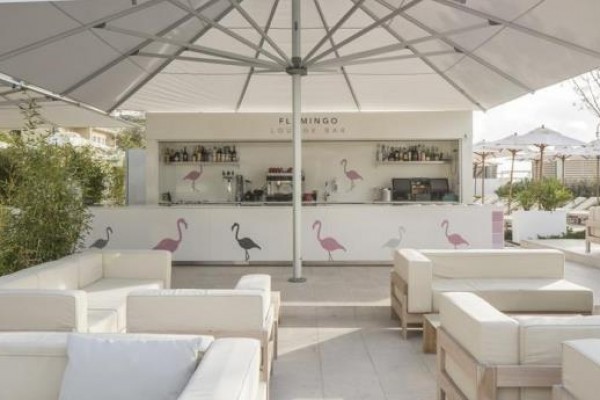 Vonkajší lounge bar s bielymi pohovkami a veľkými slnečníkmi.