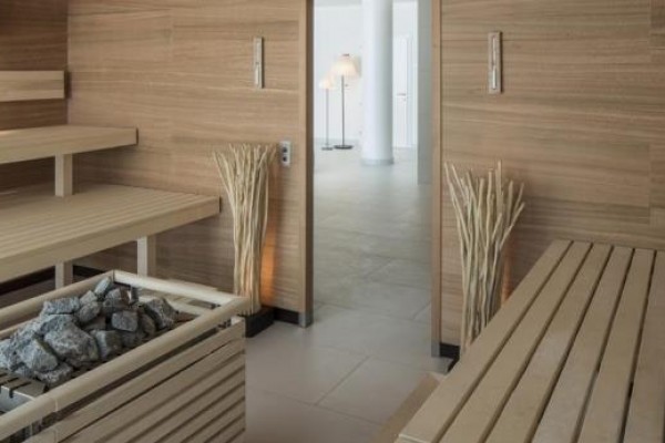 Moderná sauna s drevenými lavicami a zásobníkom na kamene.
