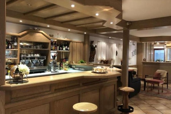 Štýlový drevený bar s nápojmi a kávovarom v elegantnej reštaurácii.