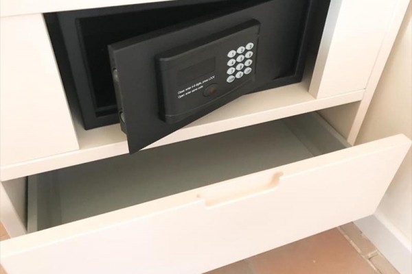 Otvorený trezor v bielom nábytku s vysunutou zásuvkou.