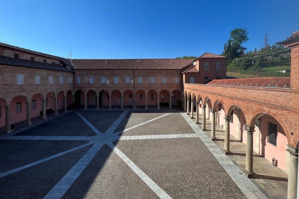 Nádvorie historickej budovy so stĺpmi a dláždenou podlahou.