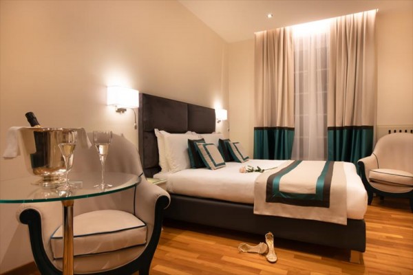 Luxusná hotelová izba s manželskou posteľou a elegantným nábytkom.