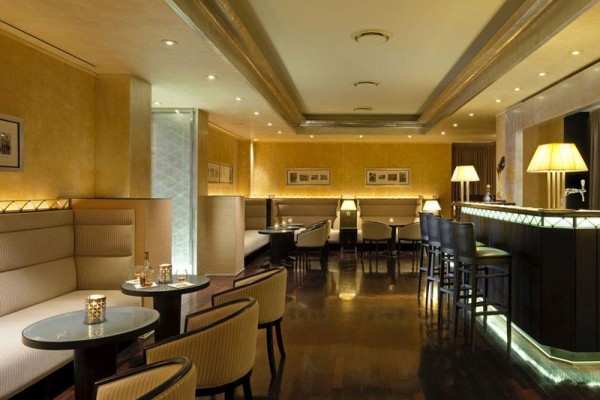 Štýlový bar s elegantnými kreslami, stolom a jemným osvetlením.  