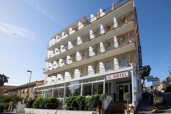 Štvorposchodový hotel s balkónmi a vstupom z ulice.