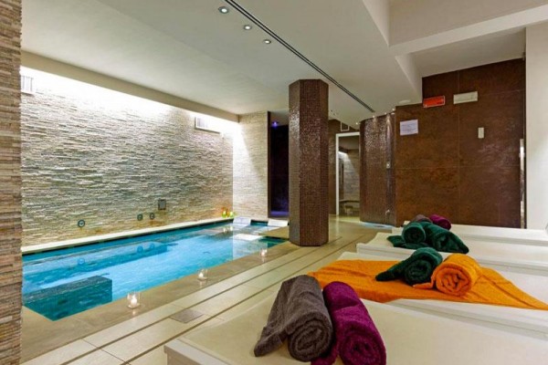 Interiér wellness centra s bazénom, lehátkami a zloženými uterákmi.