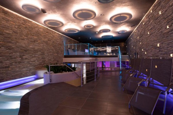 Moderný interiér wellness centra s kamennými stenami a podlahovým osvetlením.