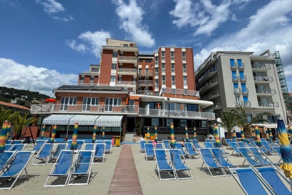 Hotel pri pláži so slnečníkmi a ležadlami.