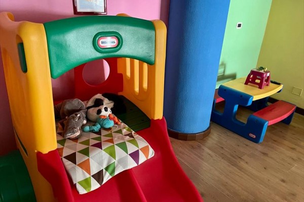 Detská šmykľavka s plyšovými hračkami a farebným stolom v miestnosti.