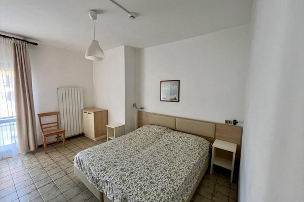 Izba s manželskou posteľou, dvoma nočnými stolíkmi, stoličkou a skrinkou pod oknom.