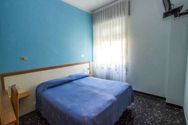 Izba s modrou stenou a manželskou posteľou pod oknom.