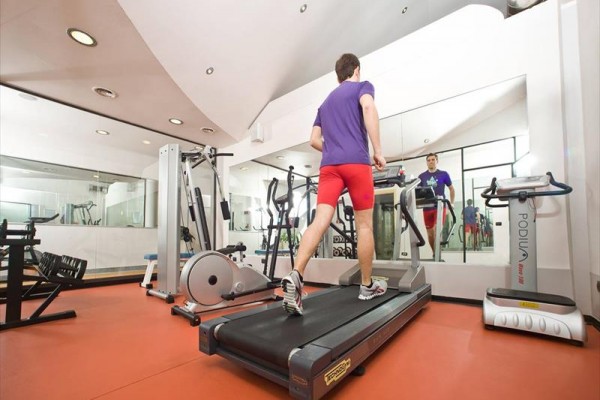 Osoba beží na bežeckom páse vo fitness centre.