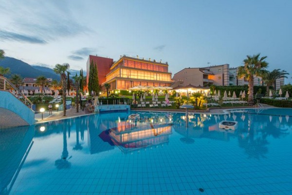 Luxusný hotel večer s osvetleným bazénom v popredí.