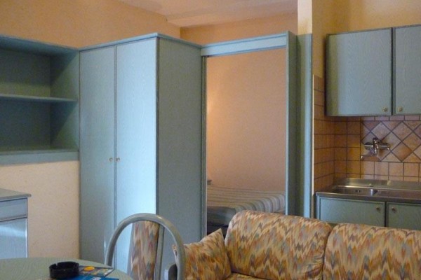 Malý apartmán s kuchynským kútom, sedačkou a skriňou.
